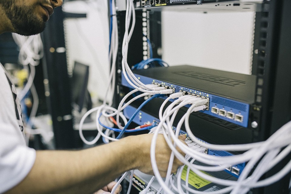 An engineer connecting network cables to a server rack switch